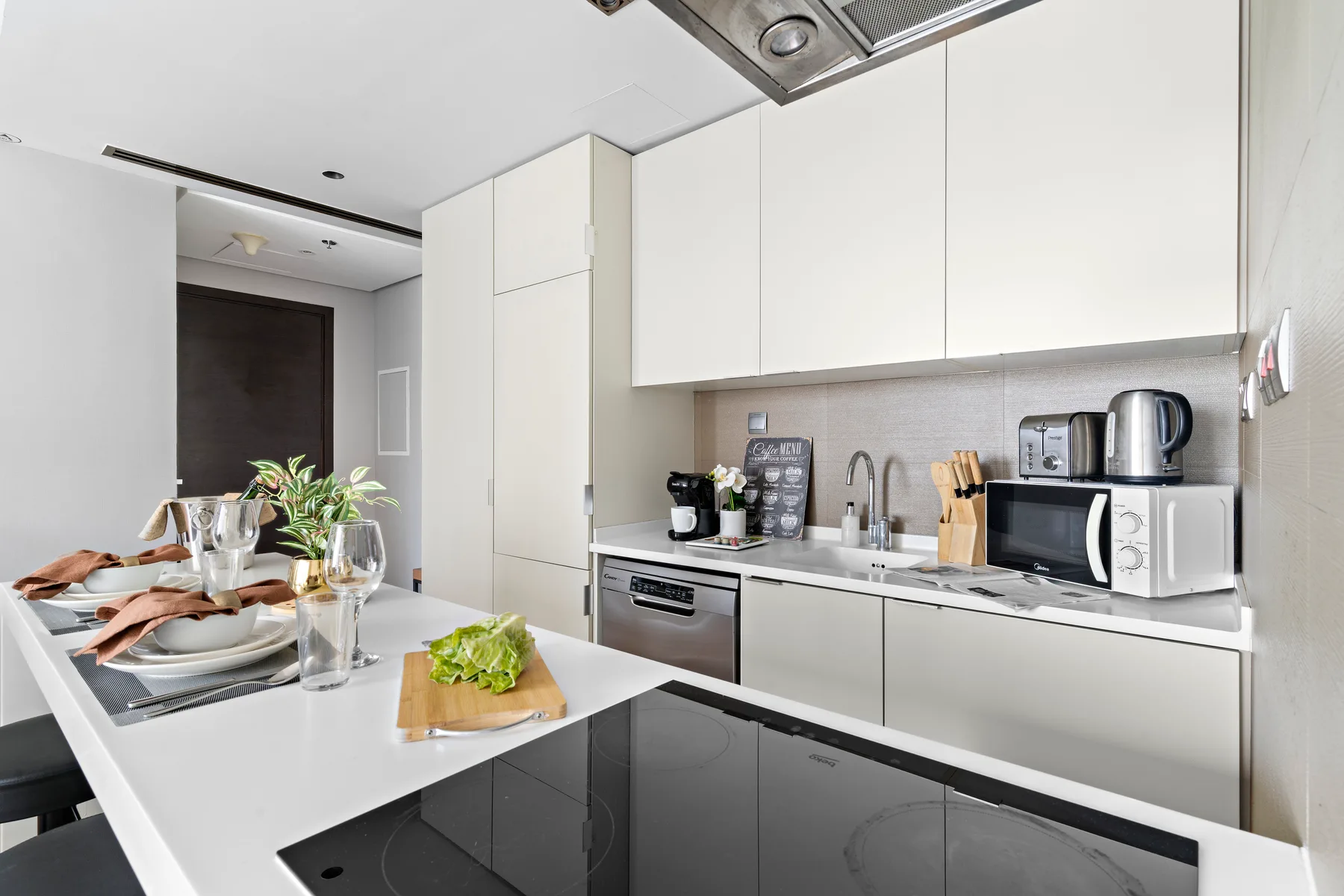 A modern kitchen with white cabinets, countertops, and a dining island.