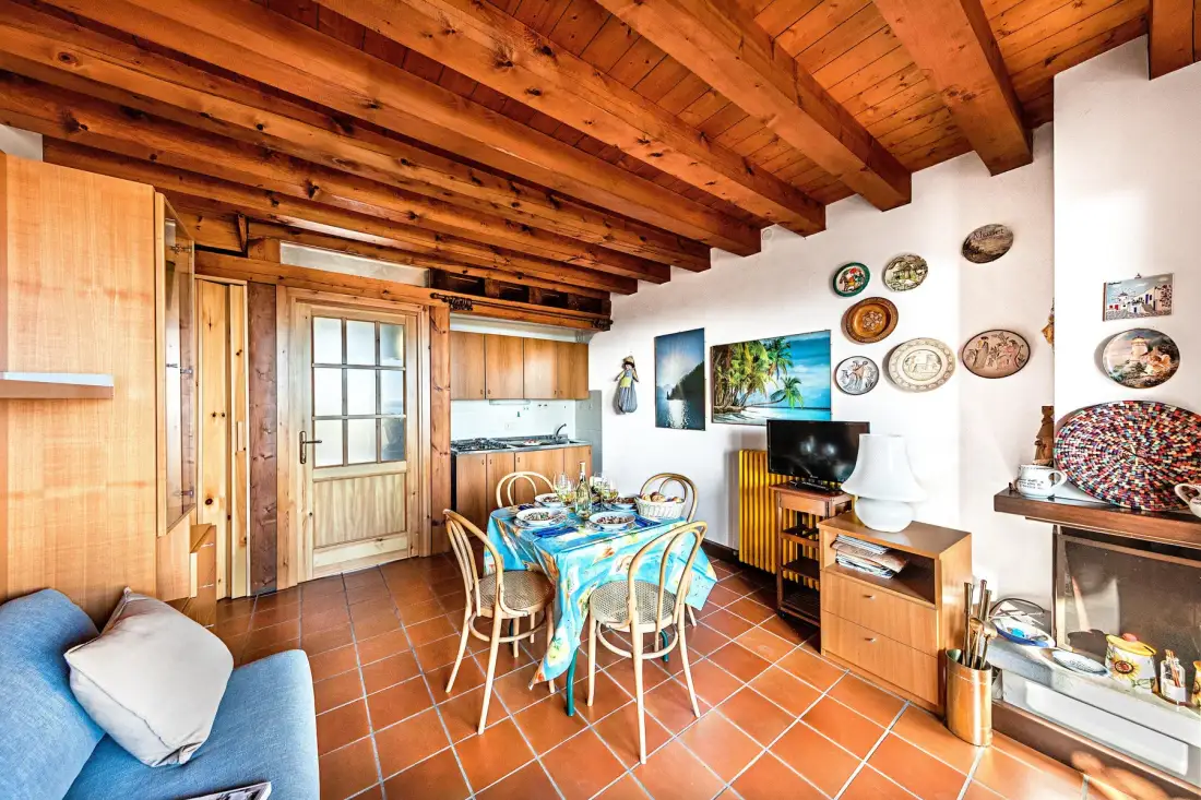 A dining area with a blue-covered table beneath exposed wooden ceiling beams.