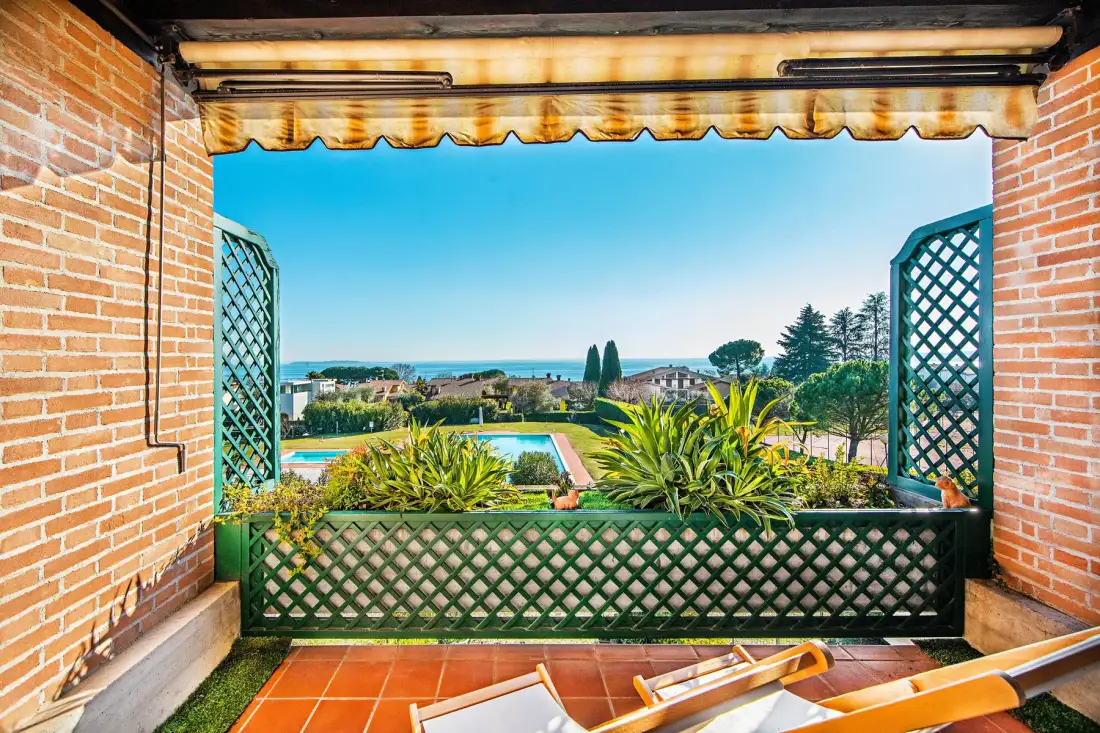 A covered terrace overlooks a swimming pool and landscaped grounds.