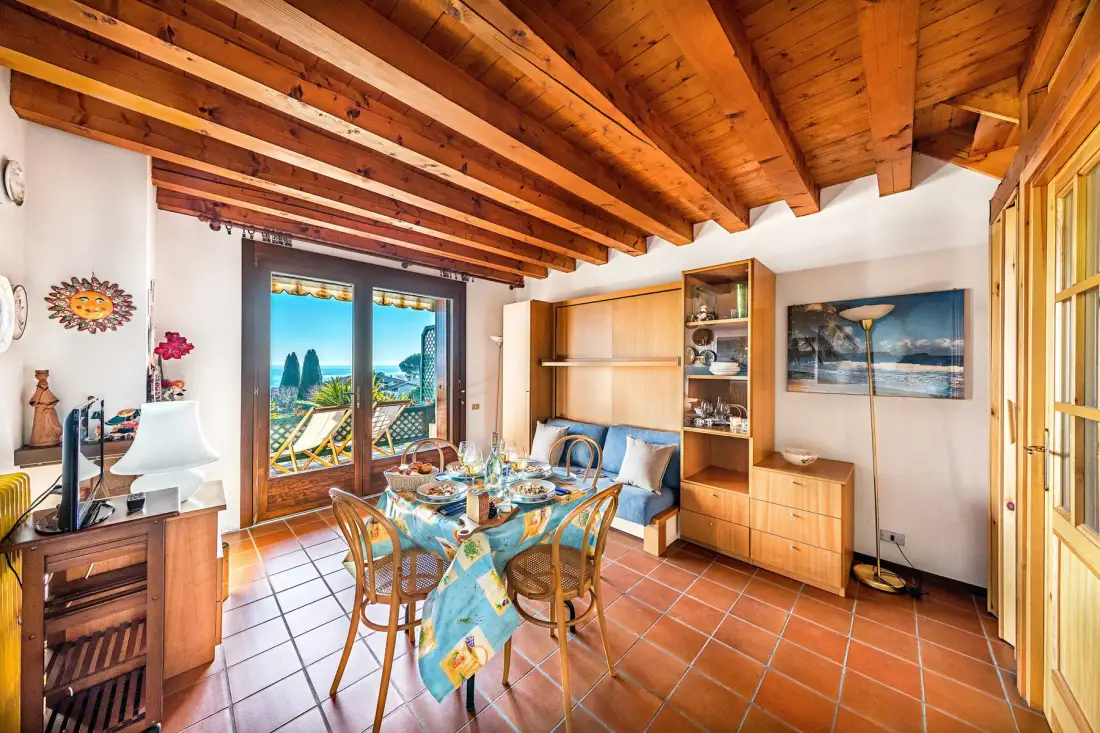 A dining area with a wooden table and chairs beneath exposed timber beams.