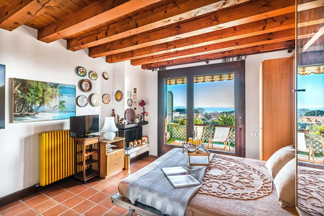 A bedroom opens onto a balcony with a view of the sea.