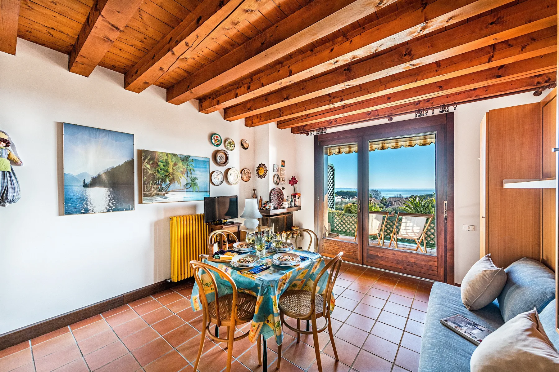A dining area with a set table beside glass doors opening onto a balcony.