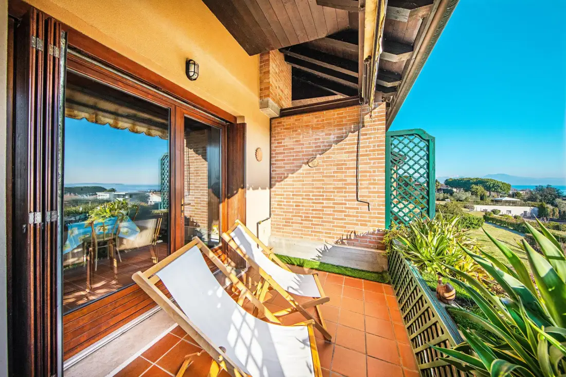 A tiled outdoor terrace with lounge seating and a view of the sea.