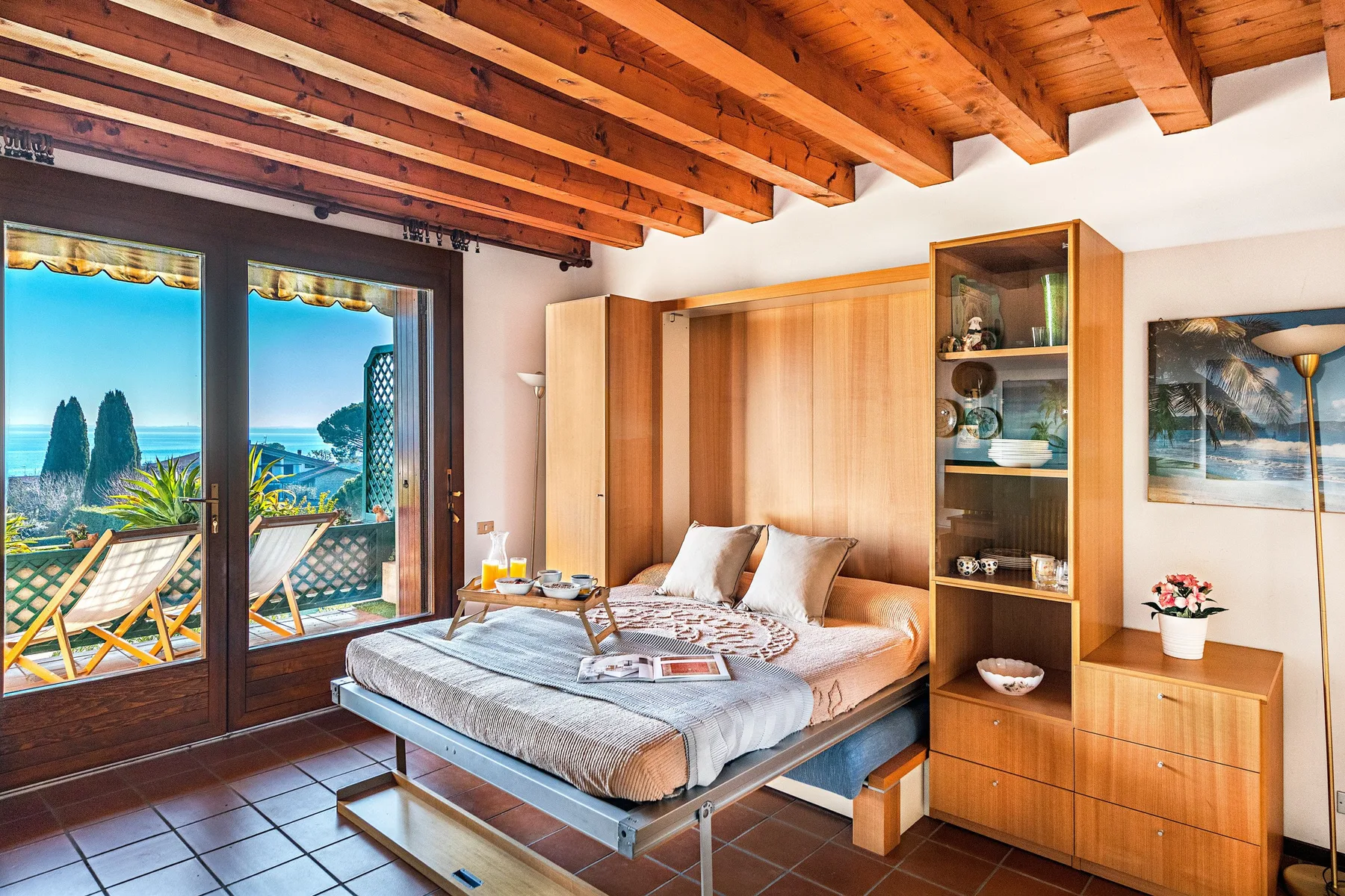 A bedroom with a bed beside glass doors opening onto a balcony.