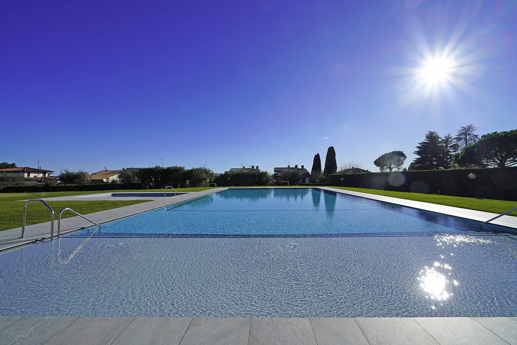An outdoor swimming pool with a shallow entry area and landscaped grounds.