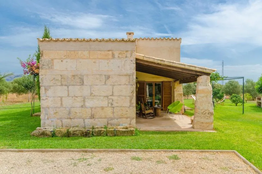 Stone building with a covered patio opening onto a green lawn.