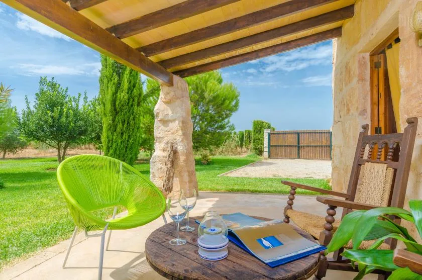 A shaded patio with seating, a table, and a garden beyond.