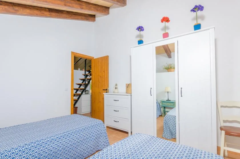 A bedroom with patterned bedding, a wardrobe, and a doorway to a staircase.