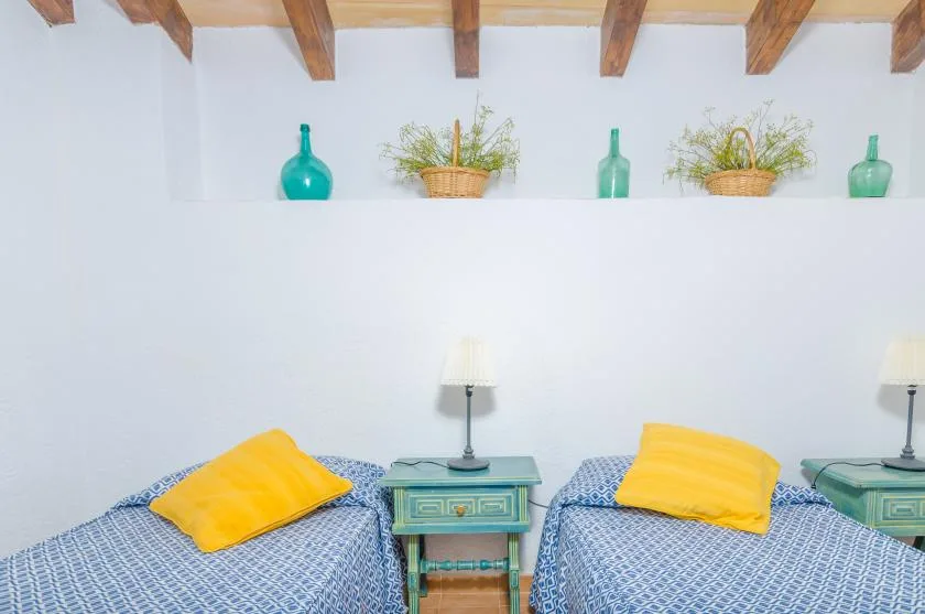 A bedroom with two beds, colorful pillows, and a small table between them.