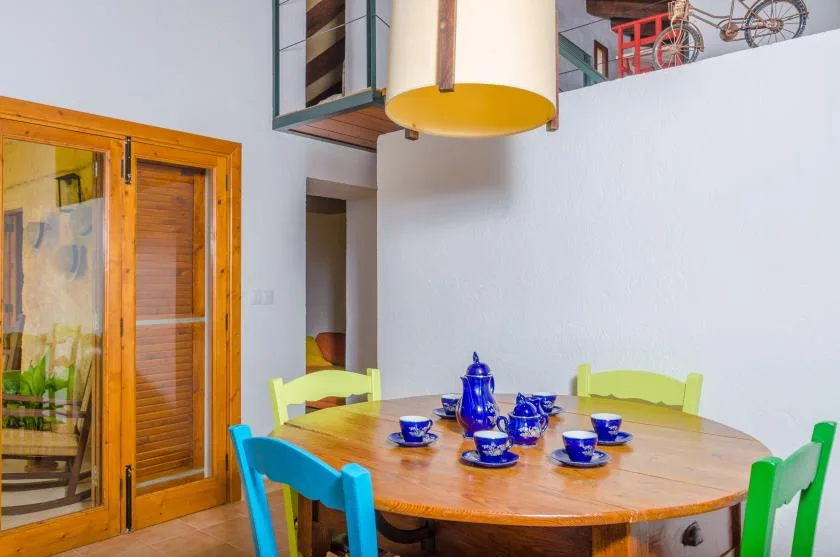 A dining area with a wooden table, colorful chairs, and blue tableware.