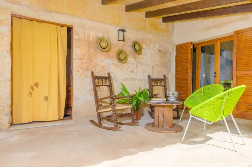 A rustic sitting area with wooden rocking chairs, a small table, and bright green seating.