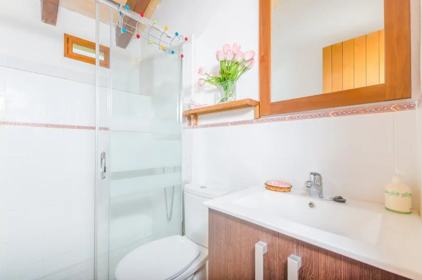 A bright bathroom with a glass shower, sink, and wooden vanity.