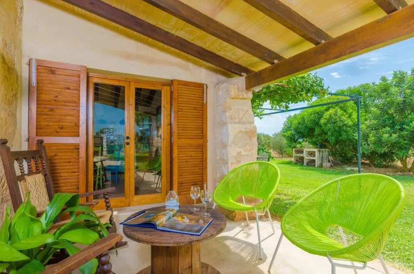 A covered patio with bright green seating and glass doors opening onto a garden.