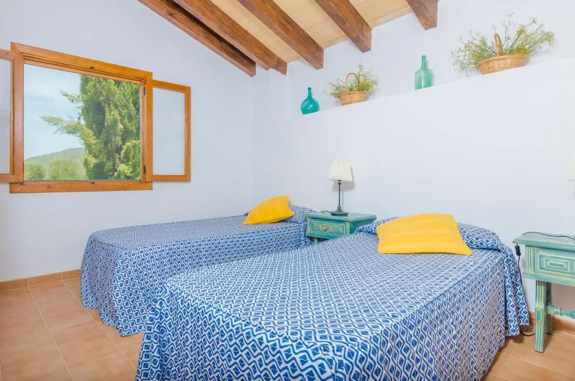 A bedroom with two beds covered in blue patterned bedding and yellow pillows.