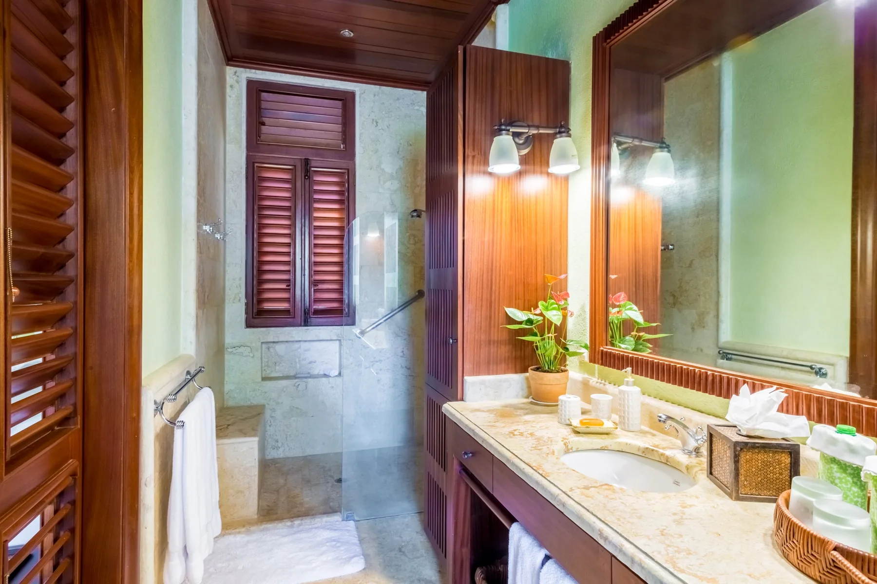 A bathroom with a long vanity, mirror, and shower area.