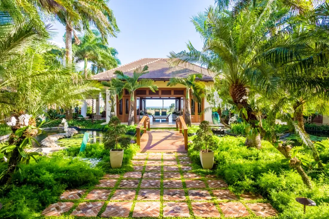 A garden path leads through tropical greenery to an open-sided pavilion.