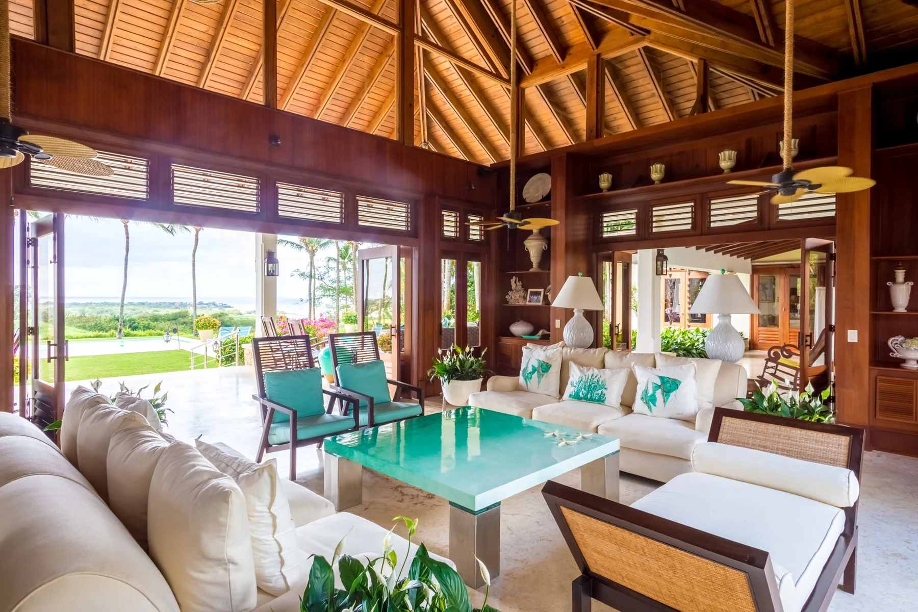 An open living room with seating around a turquoise coffee table and large windows.
