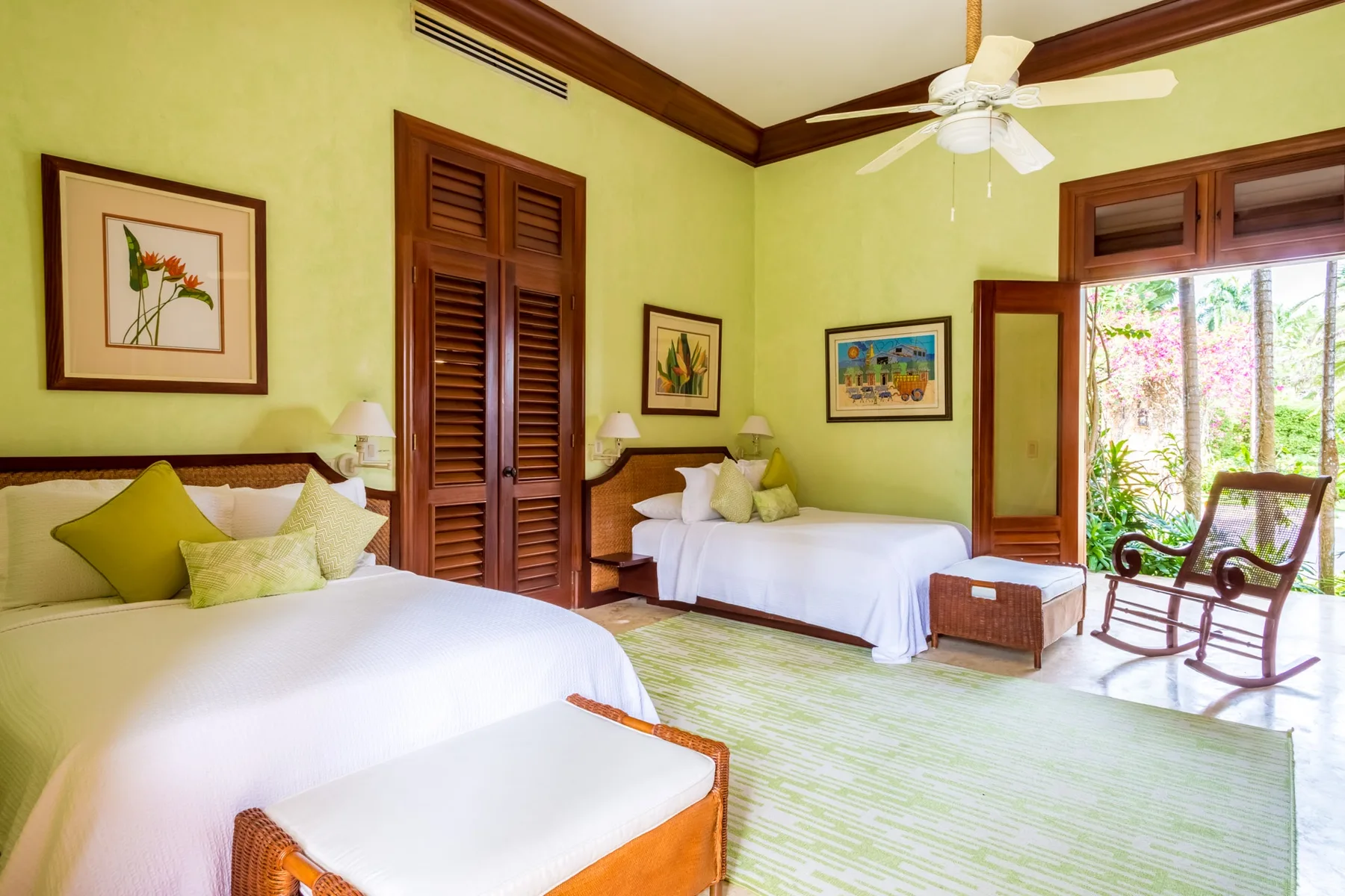 A bright bedroom with two beds and a seating area by the window.