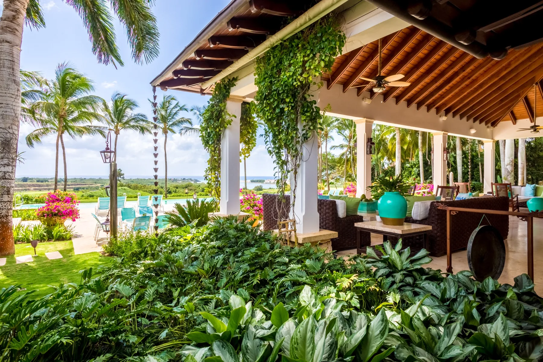 An open-air covered patio overlooks a pool and tropical landscaping.