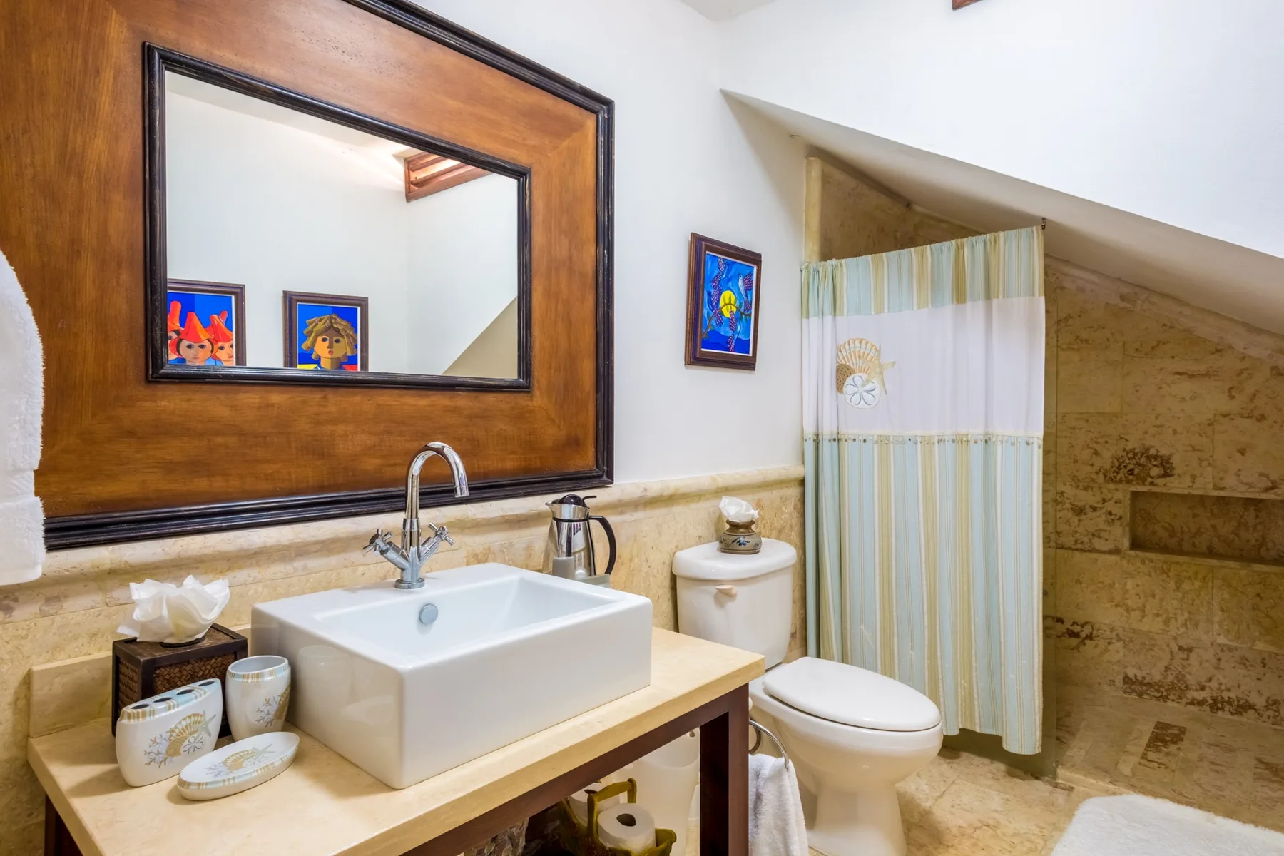 A bathroom with a sink, toilet, and curtained shower.