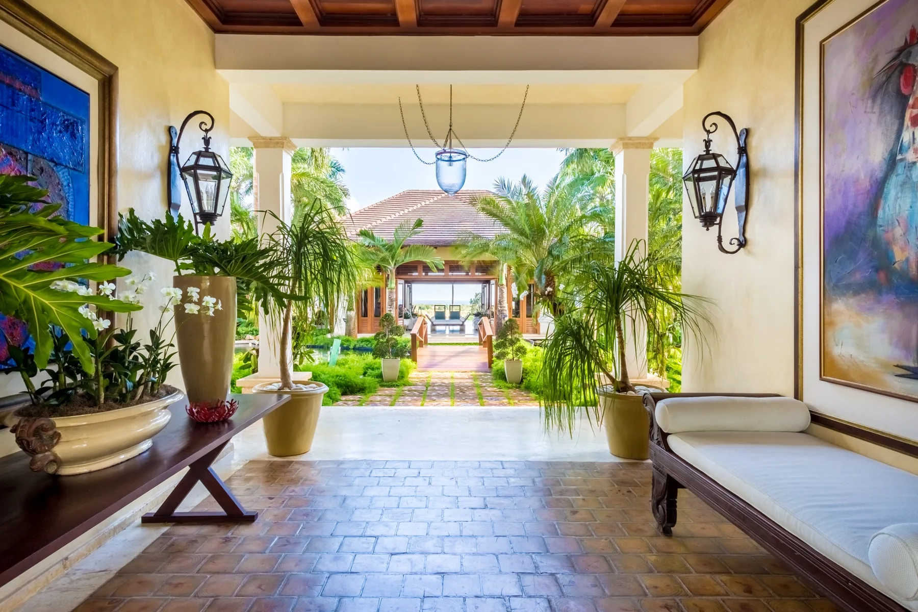 An open-sided entryway overlooks a landscaped courtyard with palms and a central walkway.