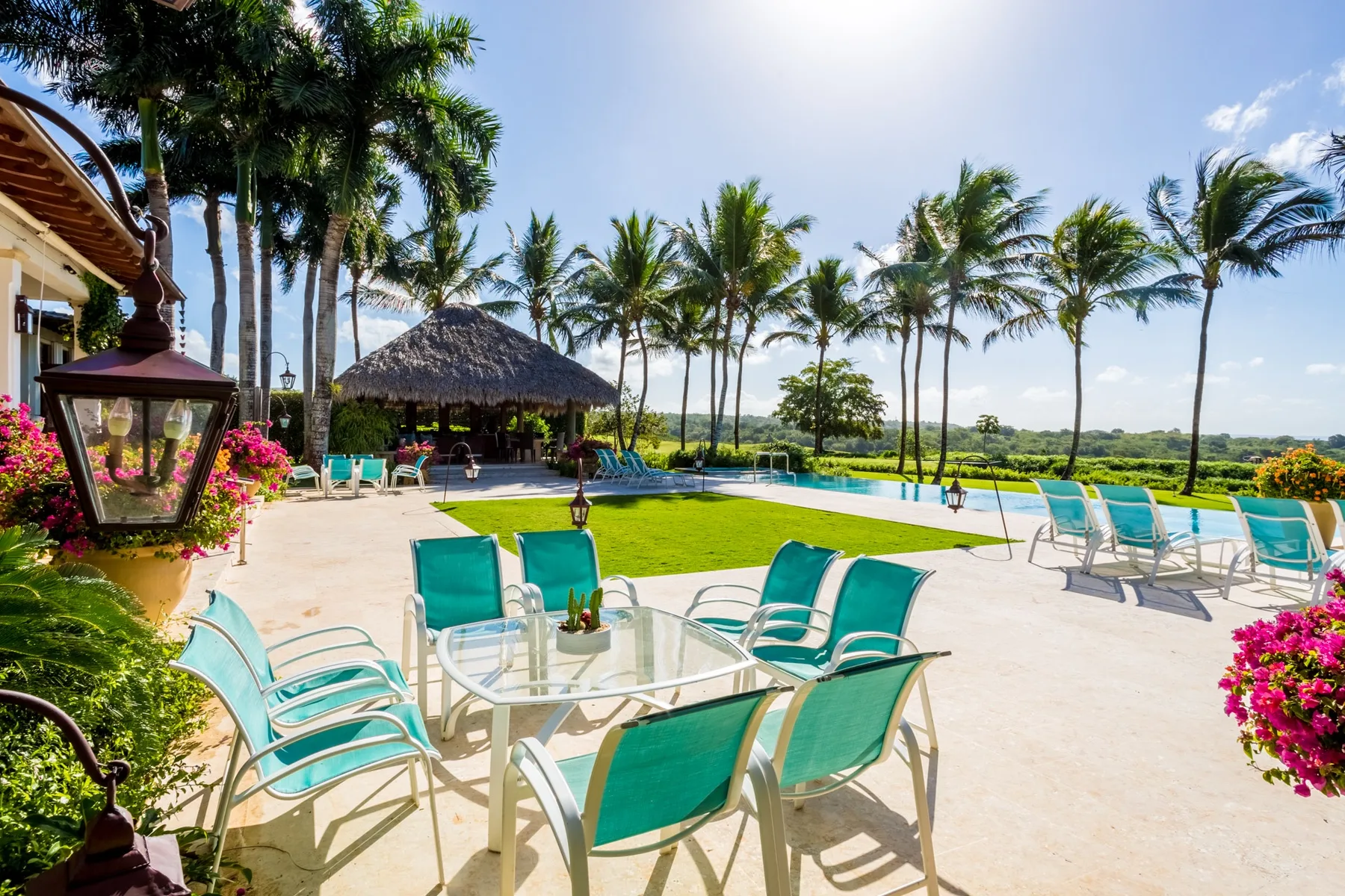 A sunny outdoor pool area with turquoise seating and palm trees.