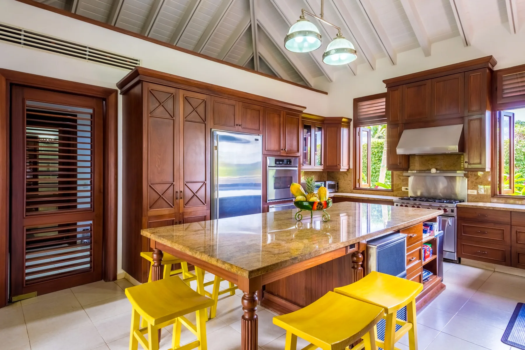 A spacious kitchen with a large island, wood cabinets, and bright windows.