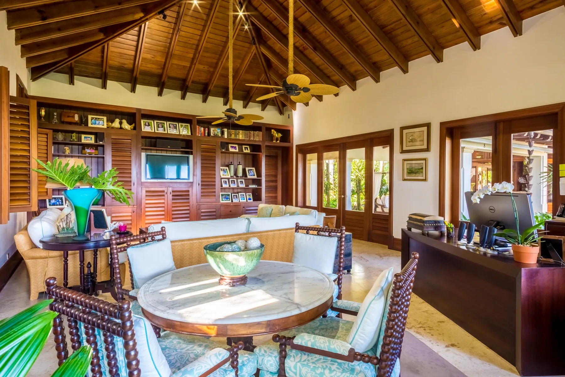 A bright living and dining area features a round table and exposed wooden ceiling.