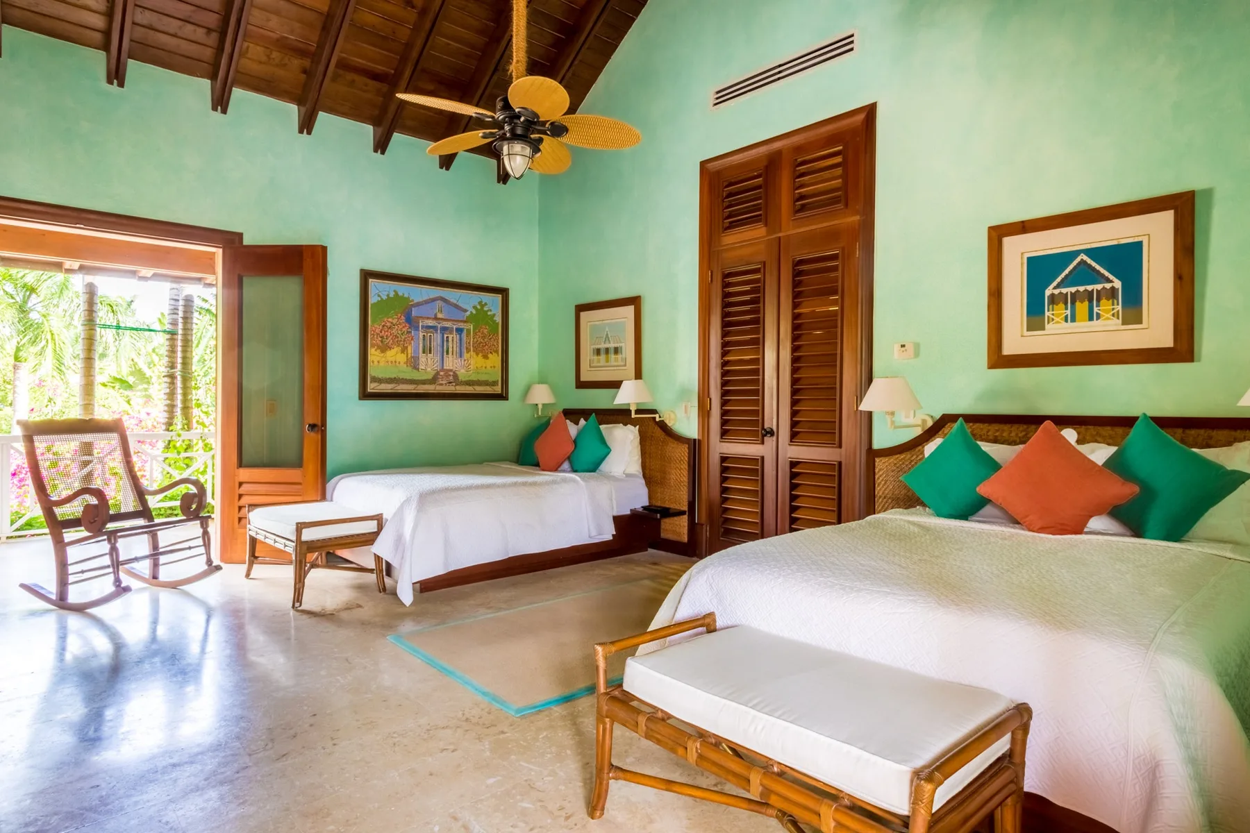 A bedroom with two beds, colorful cushions, and wooden ceiling beams.