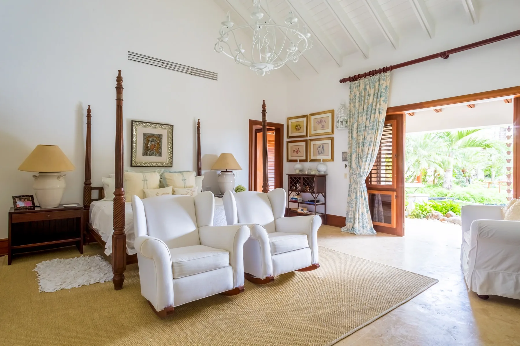 A bright living room with white seating and an open doorway to the garden.