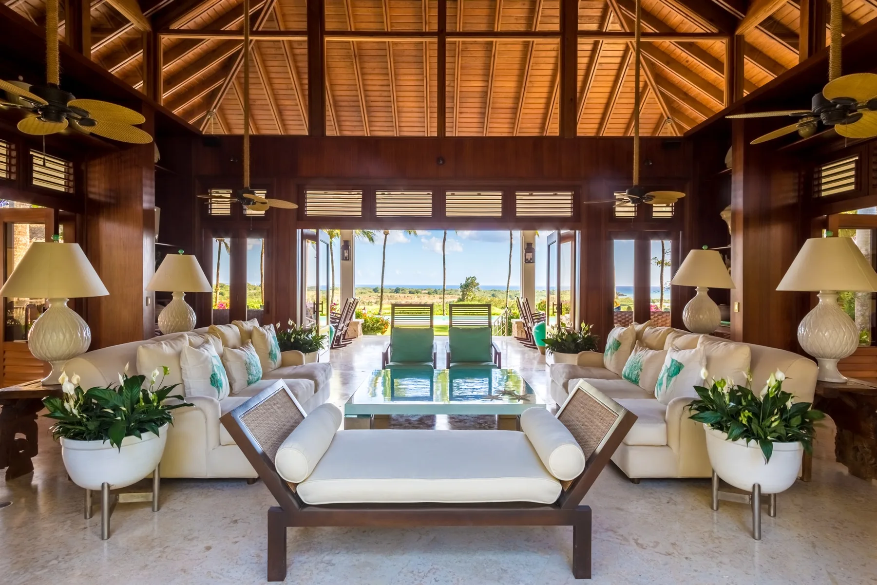 An open-sided lounge with seating arranged around a low table and a view of the water.