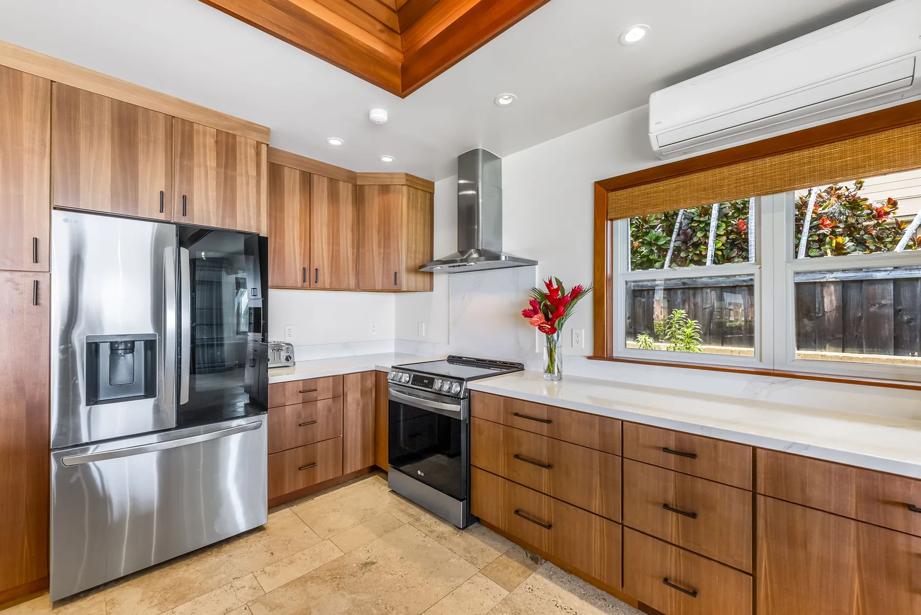 A modern kitchen with wooden cabinets, stainless steel appliances, and a wide window.