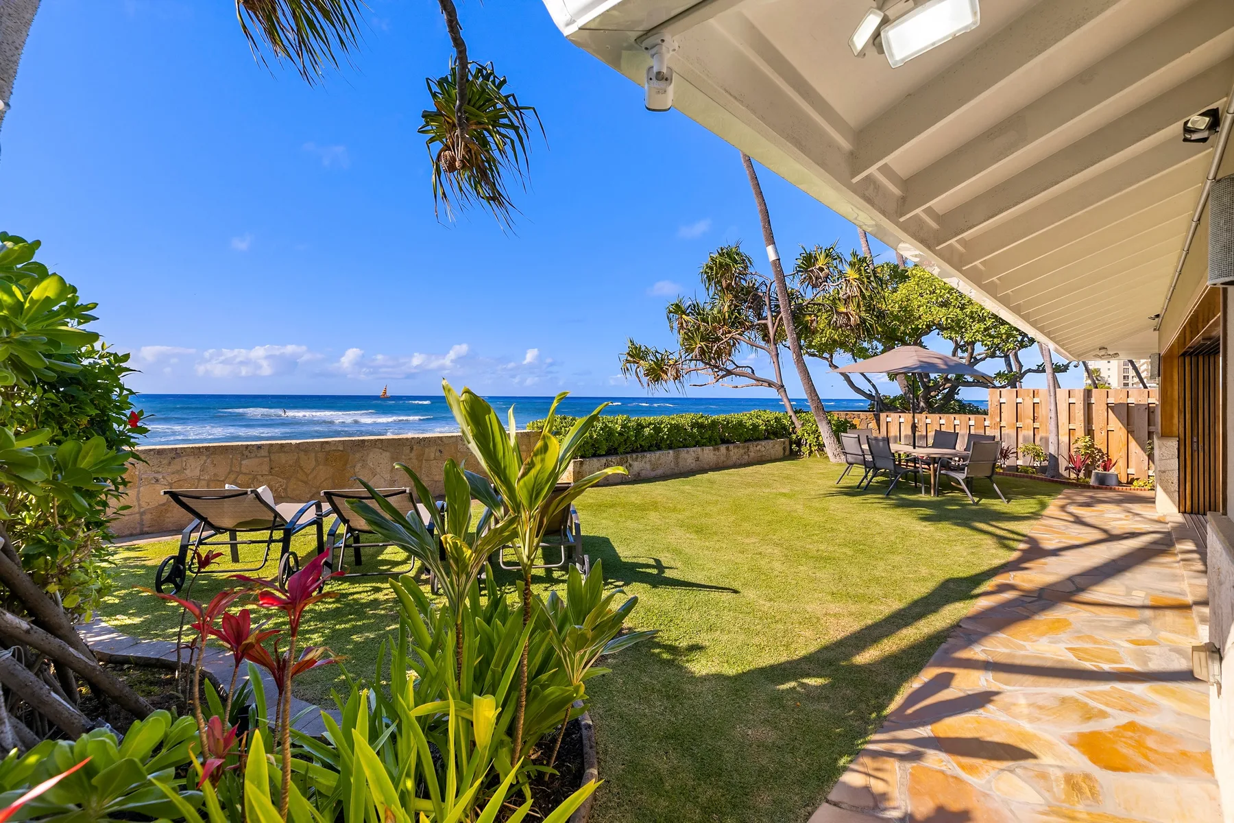 A seaside garden patio with outdoor seating, plants, and ocean views.