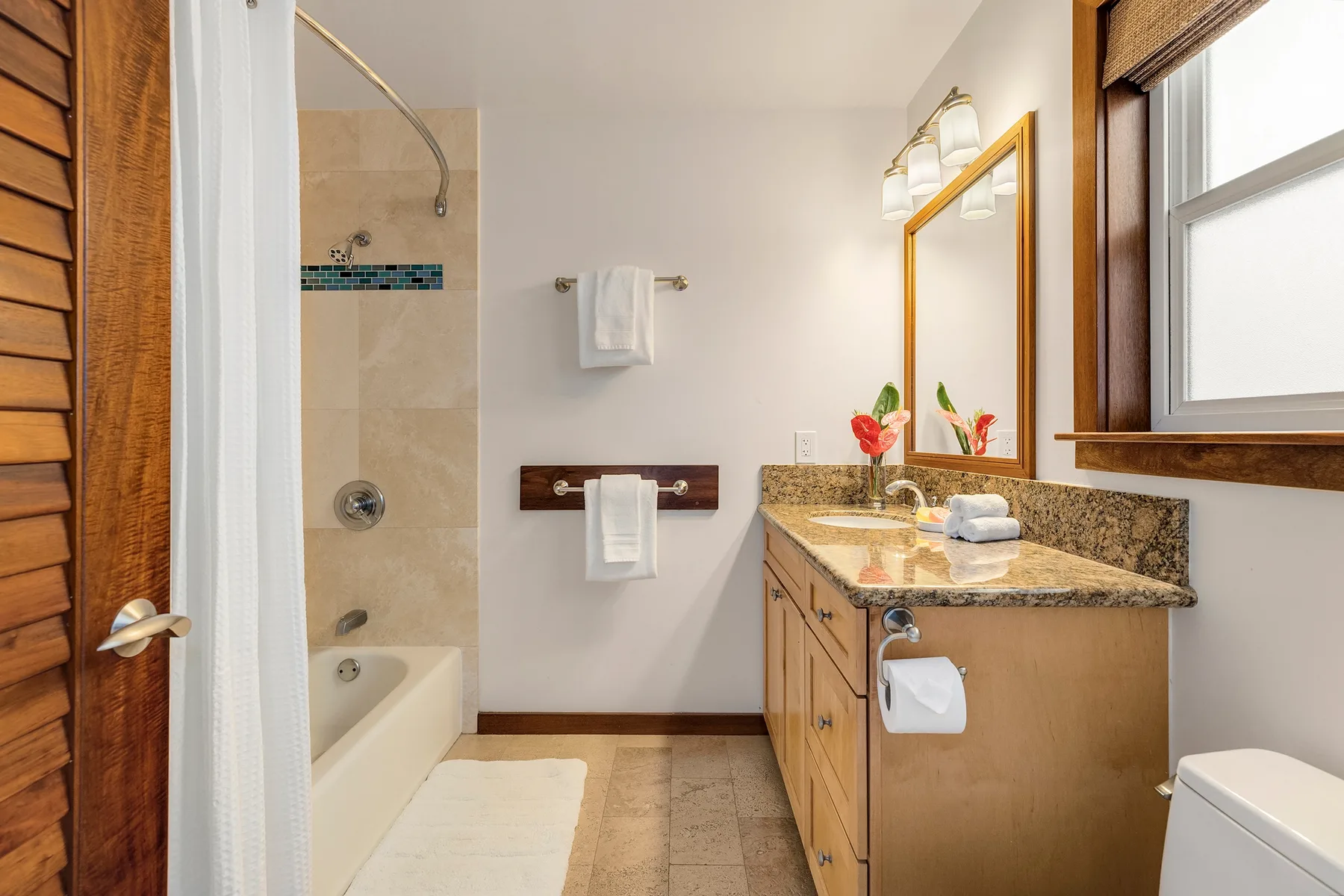 A bathroom with a shower, vanity, and mirror.