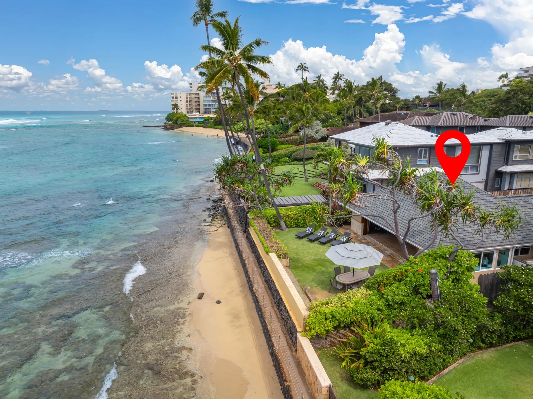 Aerial view of a beachfront property beside a sandy shore and turquoise water.