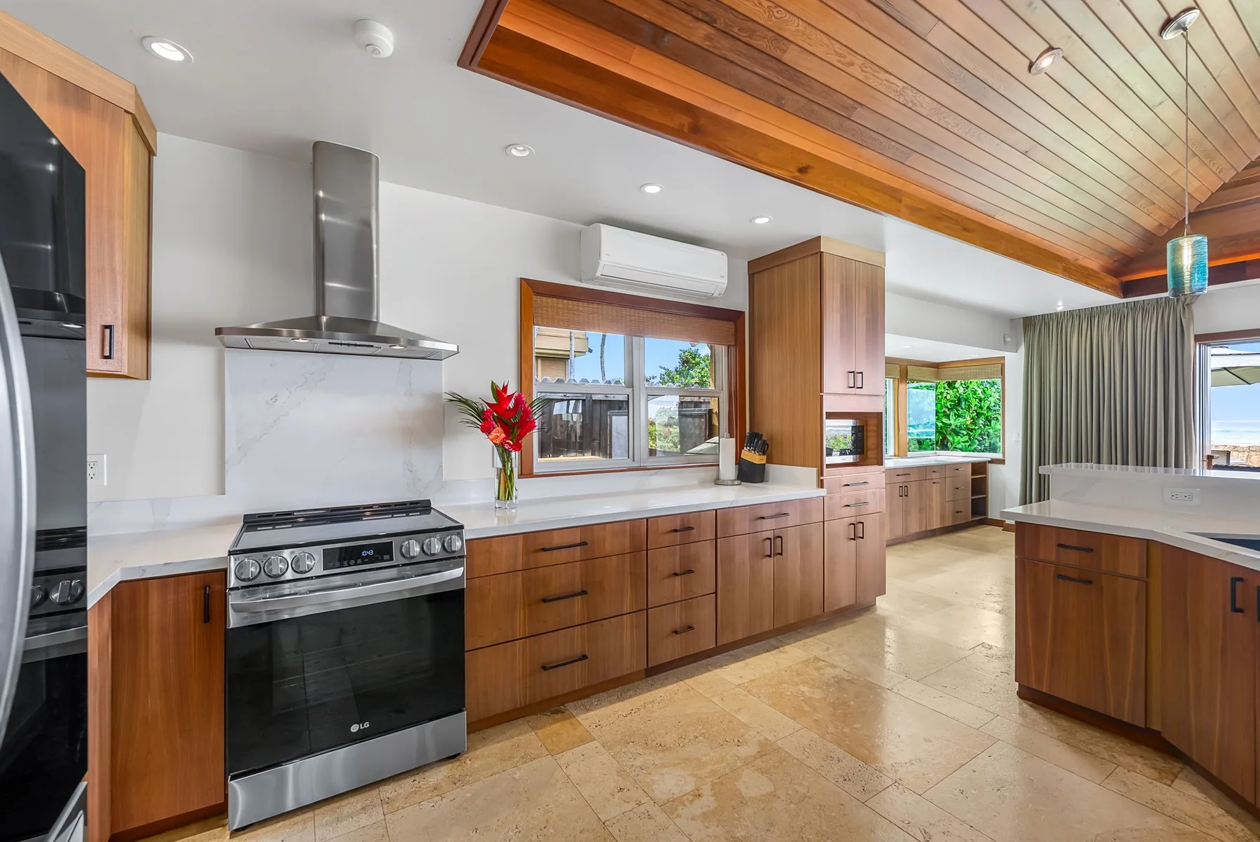 A bright kitchen with wooden cabinetry, a central island, and a stainless steel range.