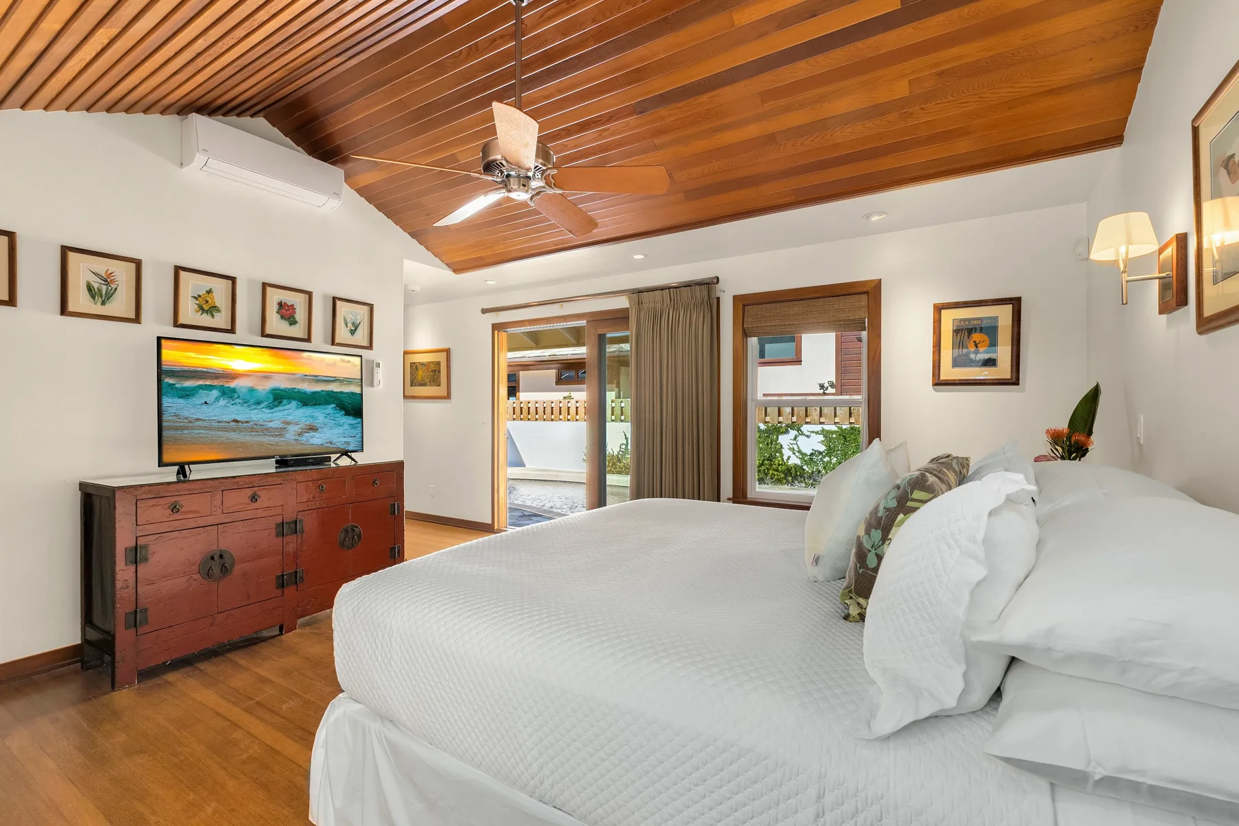 A bedroom with a large bed, wooden ceiling, and television on a dresser.