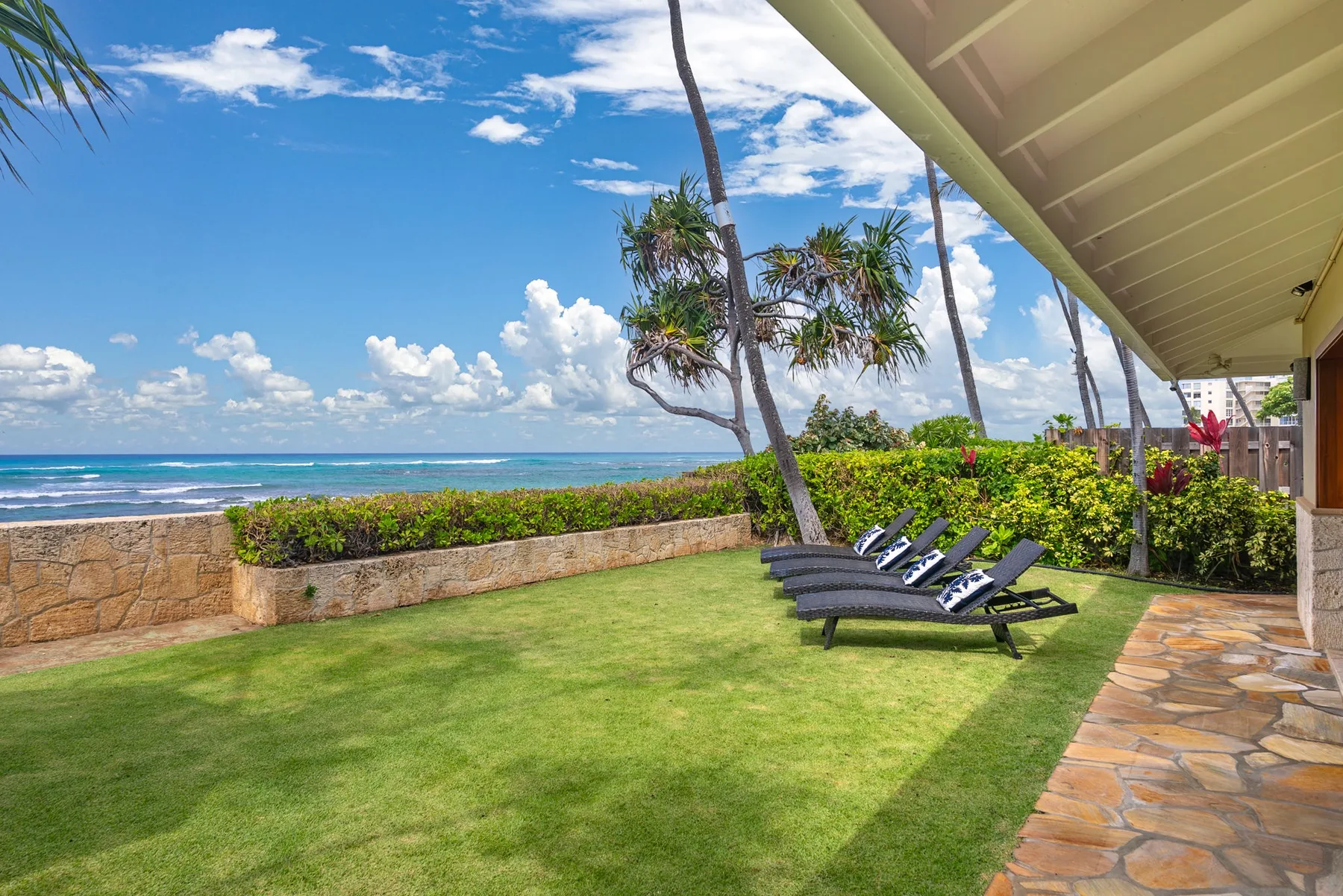 A grassy seaside lawn with reclining chairs faces the ocean.