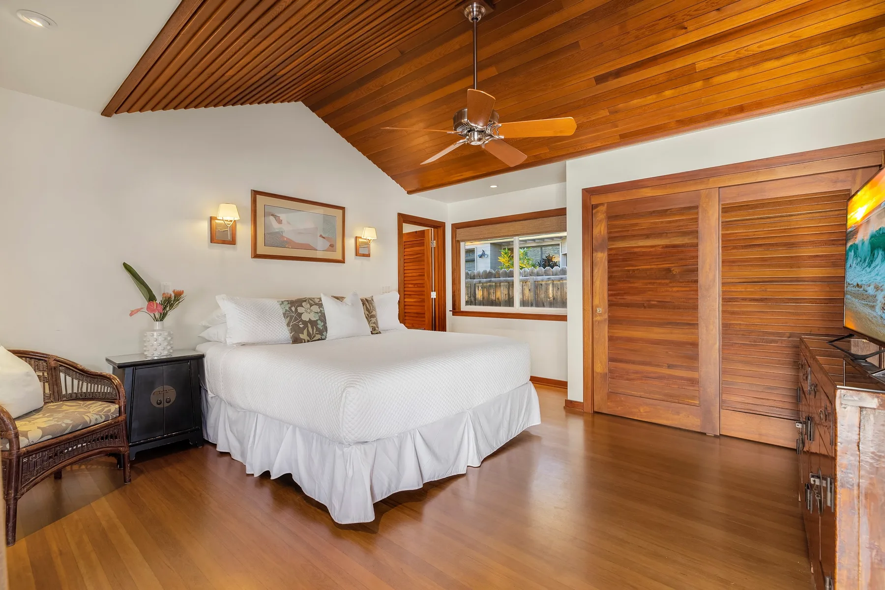 A bedroom with a large bed beneath a wood-paneled ceiling.