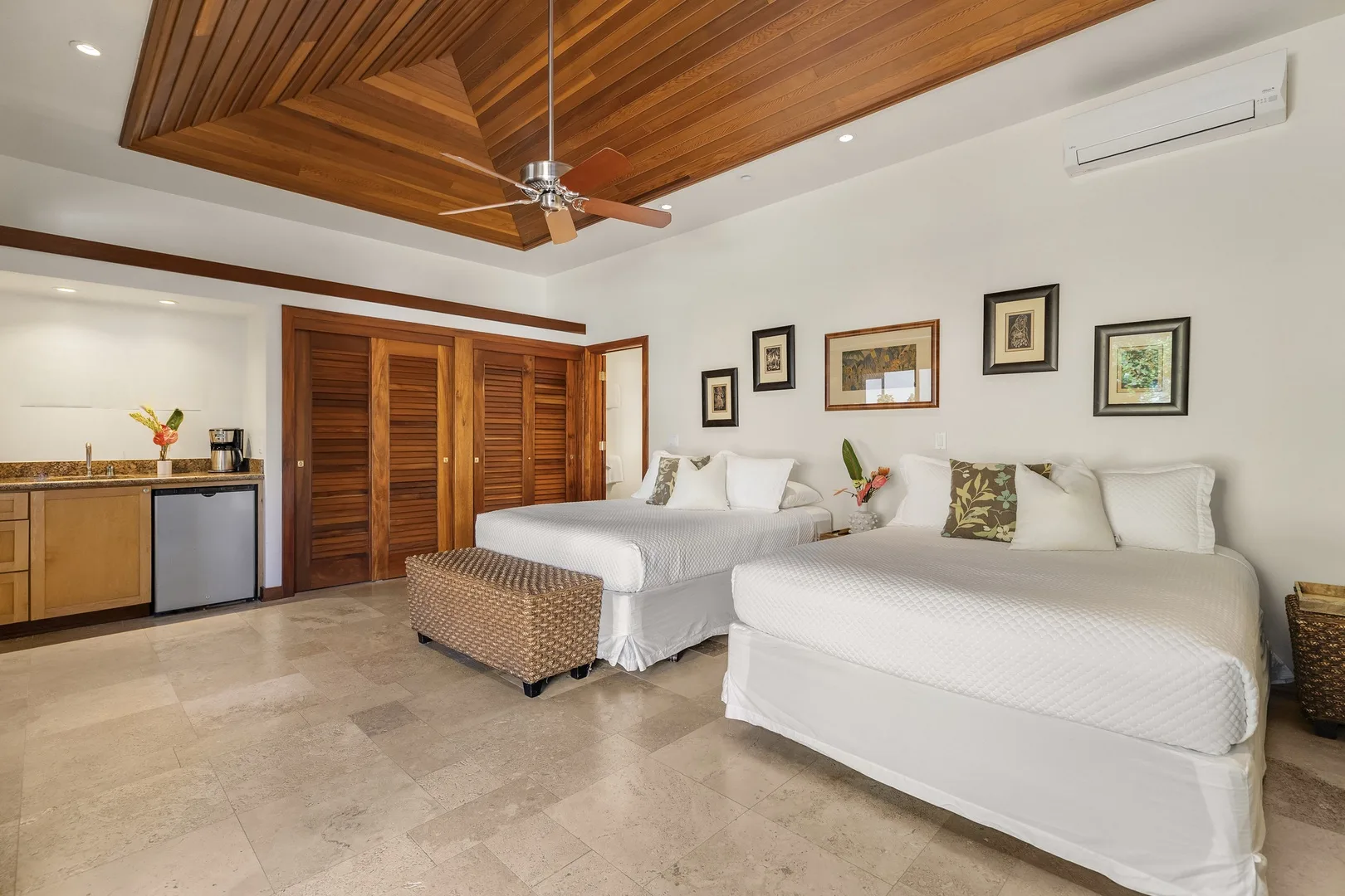 A bedroom with two beds, framed artwork, and a wooden ceiling.
