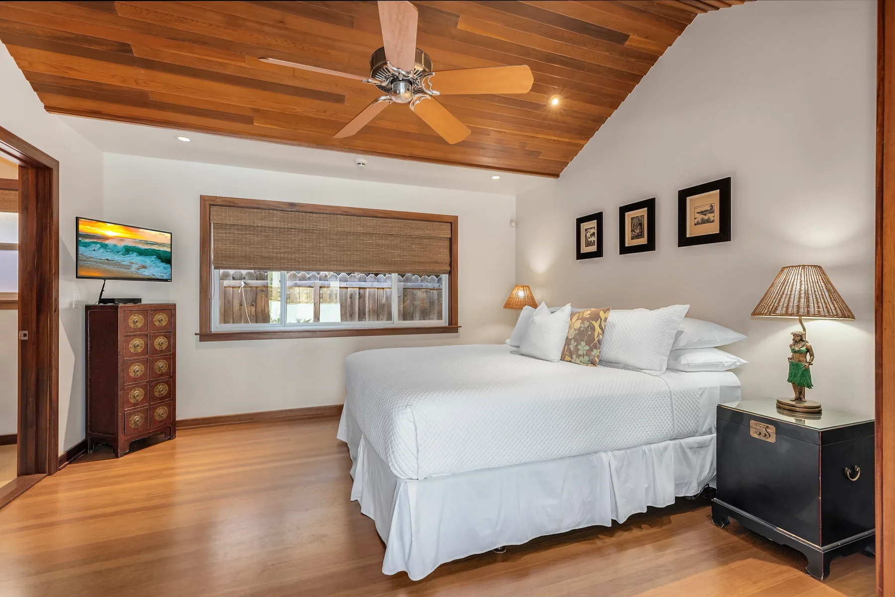 A bedroom with a large bed beneath a wood-paneled ceiling.