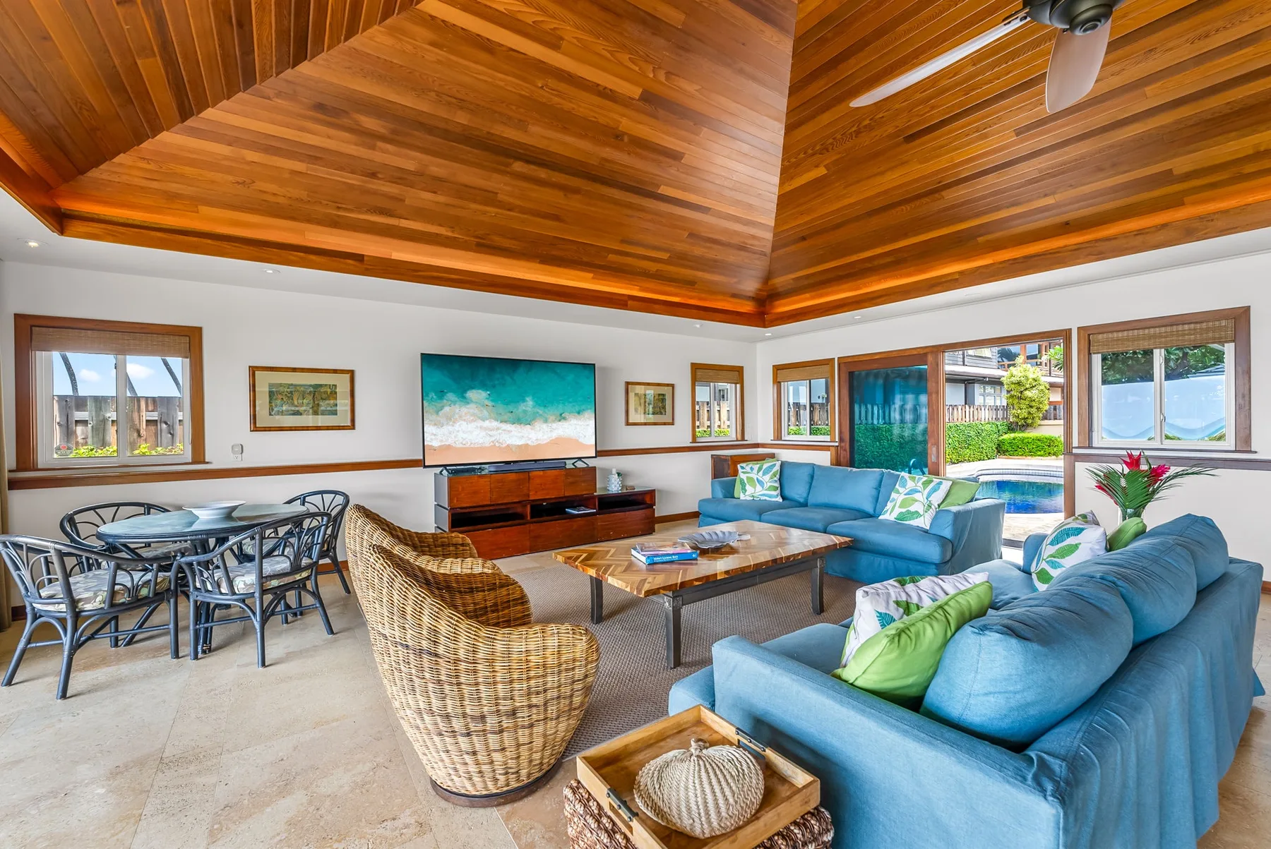 Living room with blue seating, a coffee table, and windows overlooking a garden.