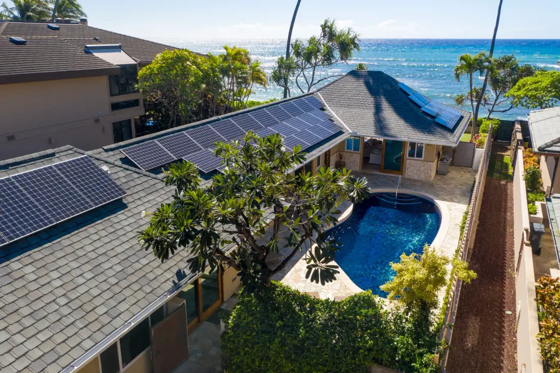 A coastal property with a swimming pool and solar panels, overlooking the ocean.