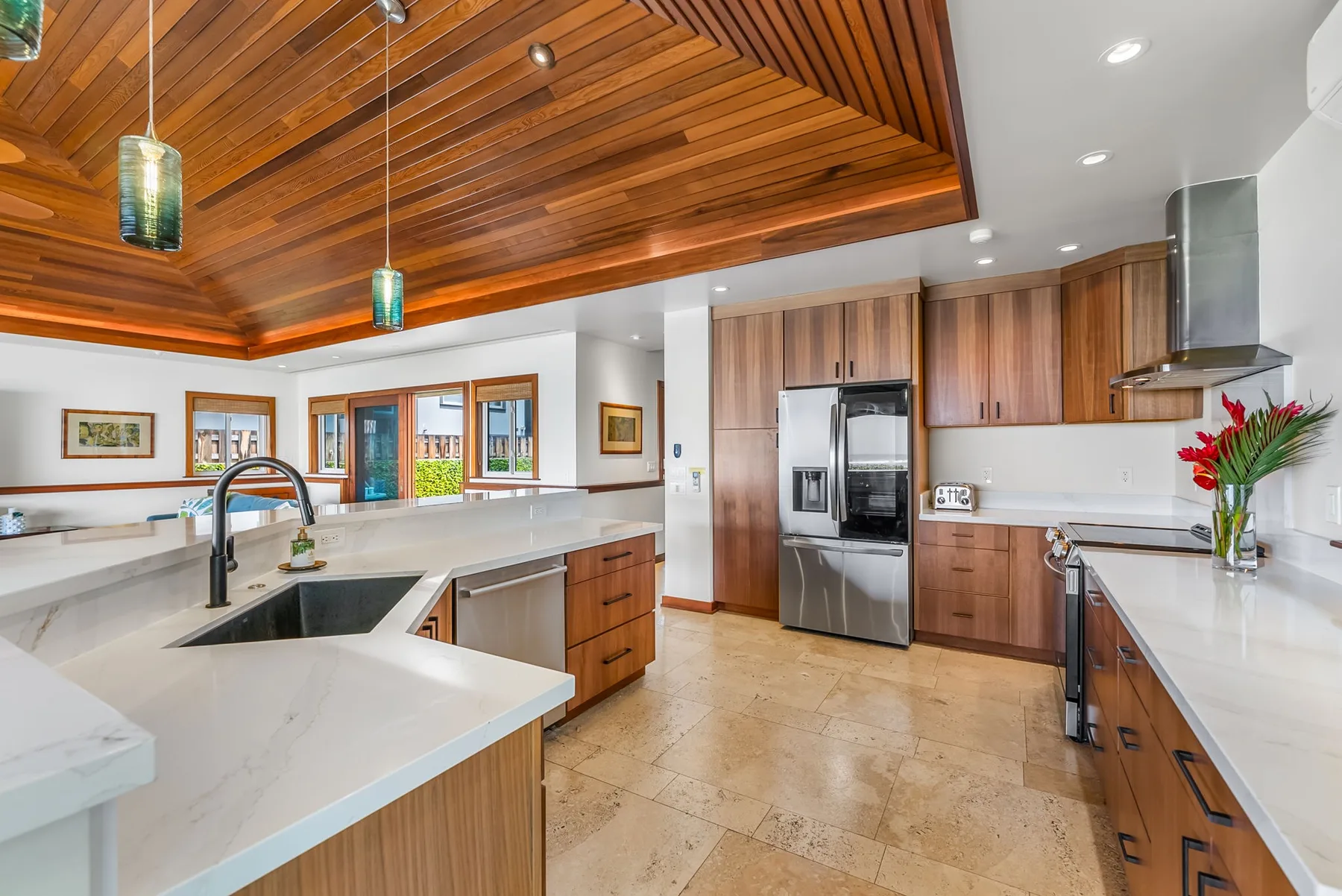 A bright kitchen with a large island, wood cabinetry, and stainless steel appliances.