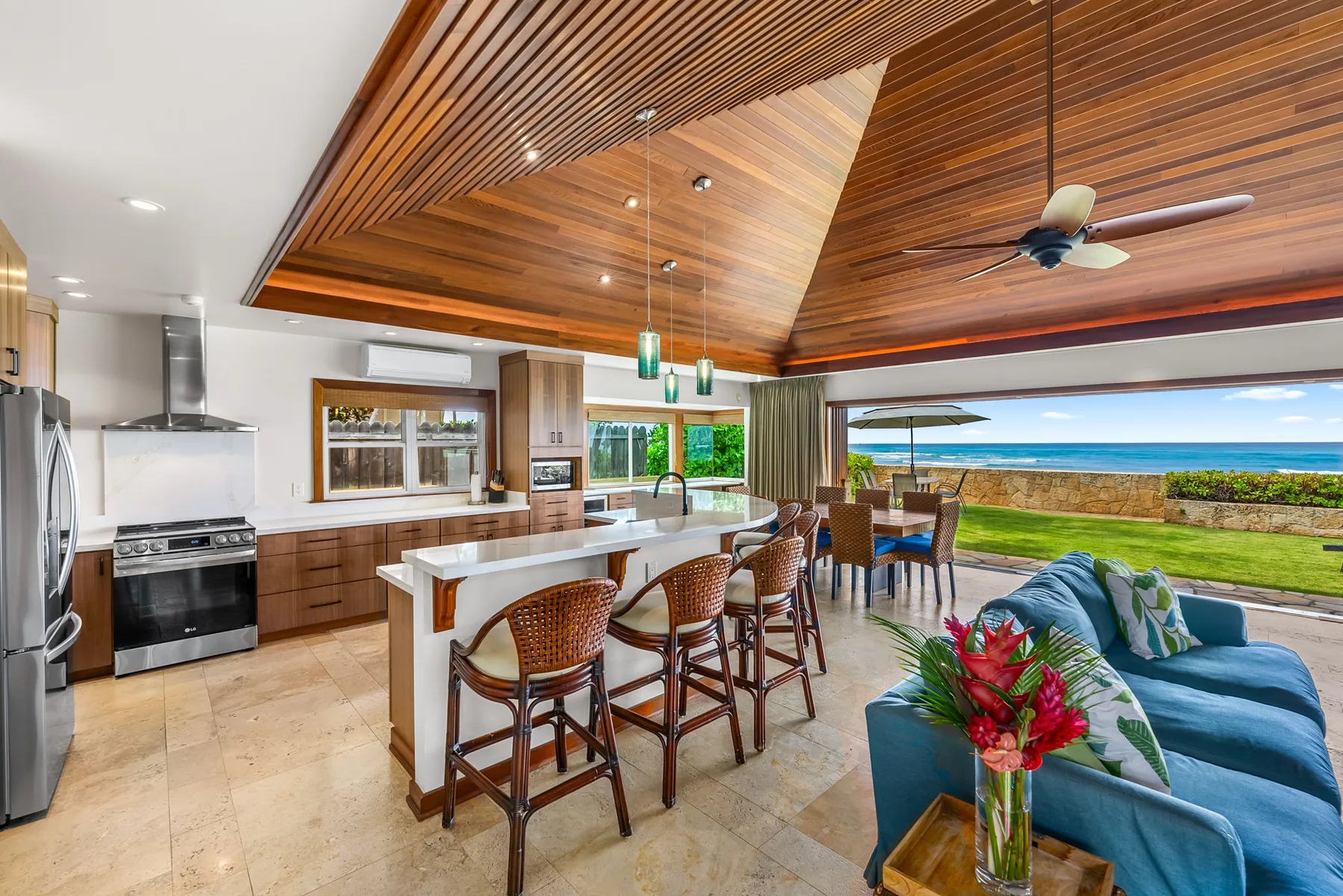 An open kitchen and dining area faces a living space and ocean view.