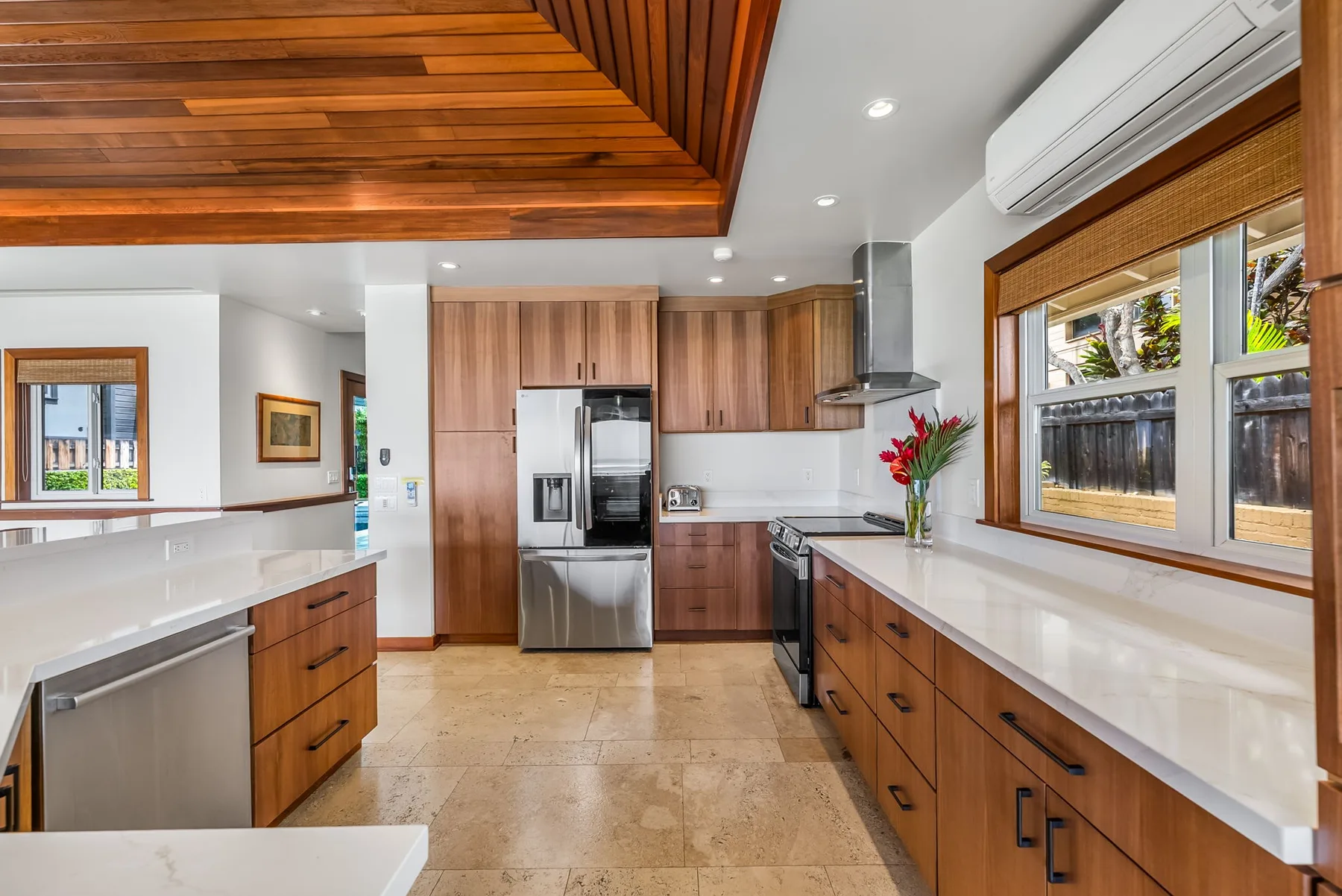 A bright kitchen with wooden cabinets, stainless steel appliances, and long countertops.