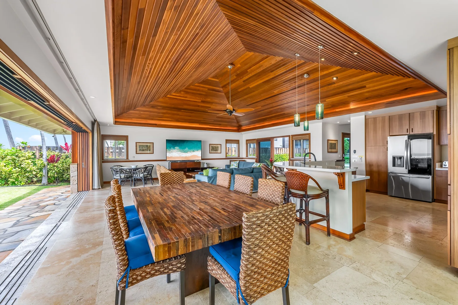 An open dining and kitchen area with a long wooden table and blue seating.