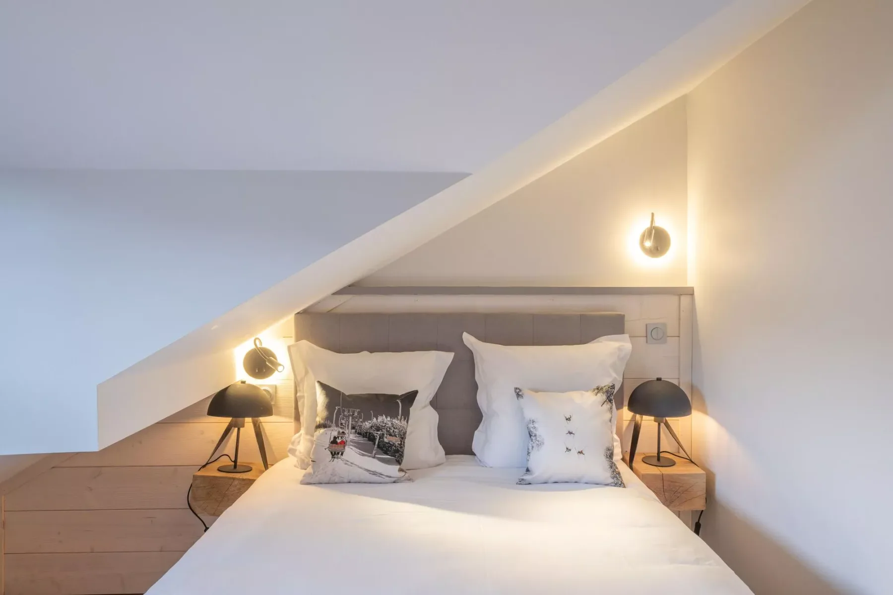 A bedroom with a bed tucked beneath a sloped ceiling.