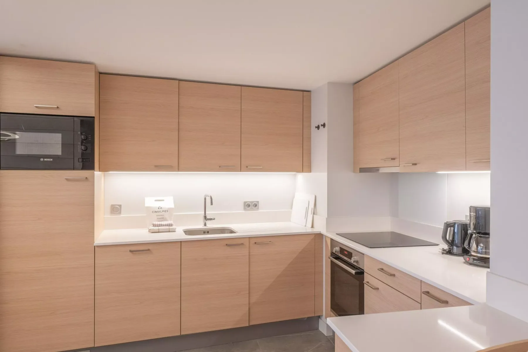 A modern kitchen with light wood cabinets and a white countertop.