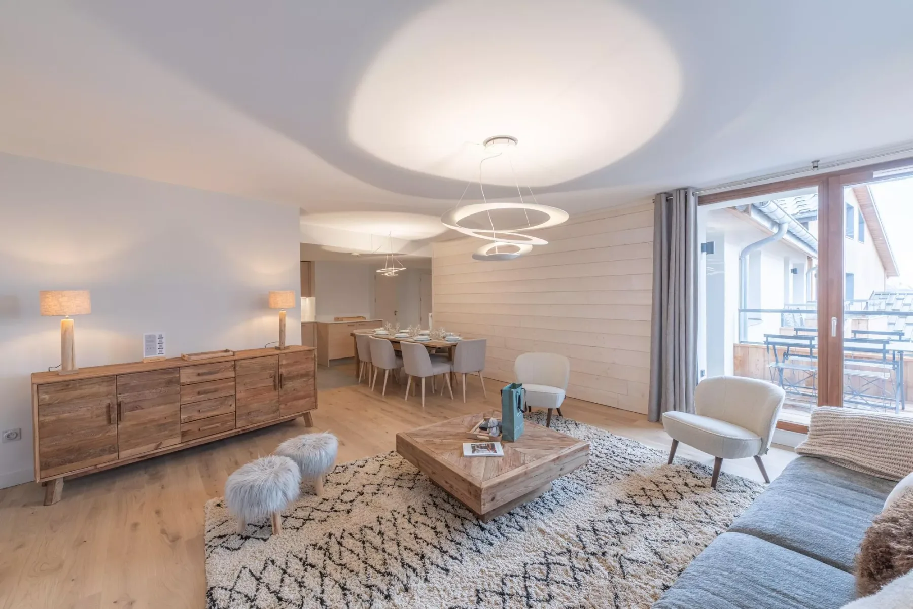 A bright living room with a dining area and large windows opening onto a balcony.